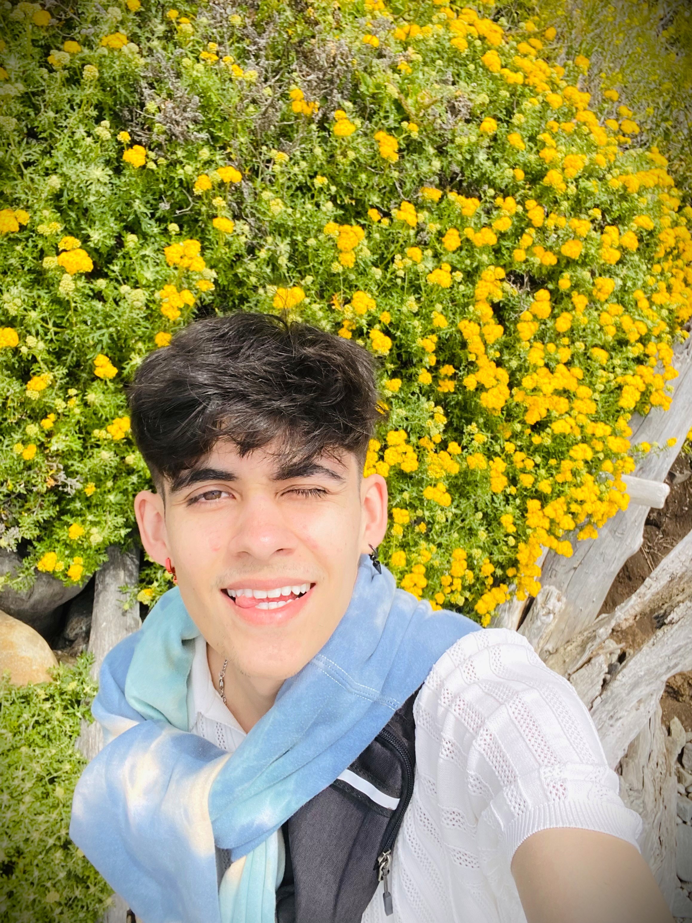 Miko with a tie-dye blue hoodie wrapped around the neck with a white color T-shirt. There was a huge bed of little yellow popping flowers behind me that made me think about sunflowers.